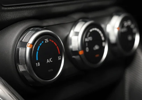 Close-up of car AC temperature controls inside a vehicle dashboard with climate settings displayed.